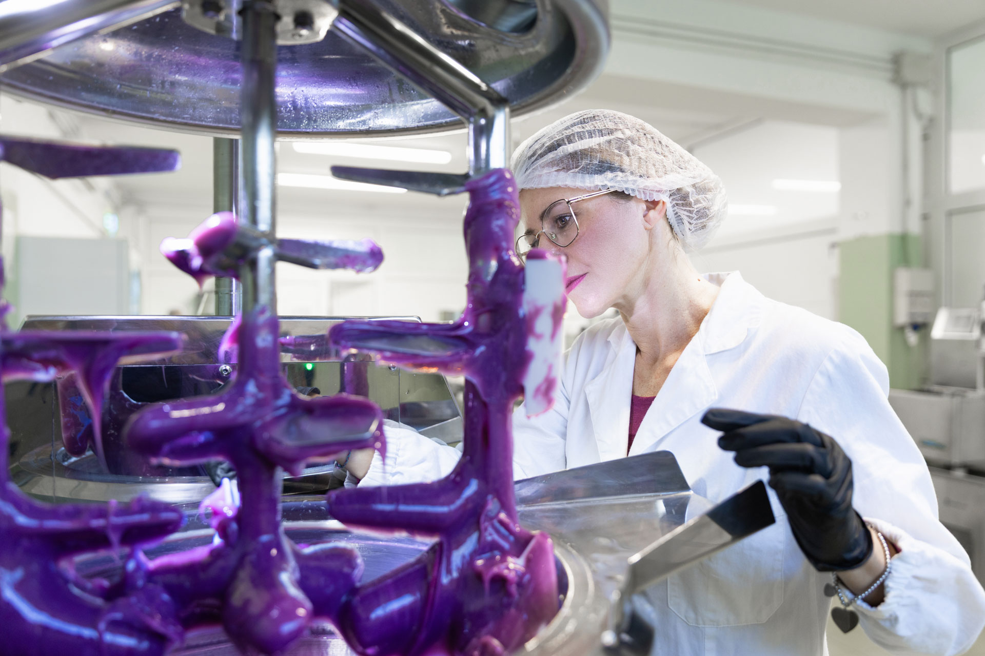 Scienziata in camice che controlla la miscelazione di un prodotto cosmetico nel laboratorio di produzione.