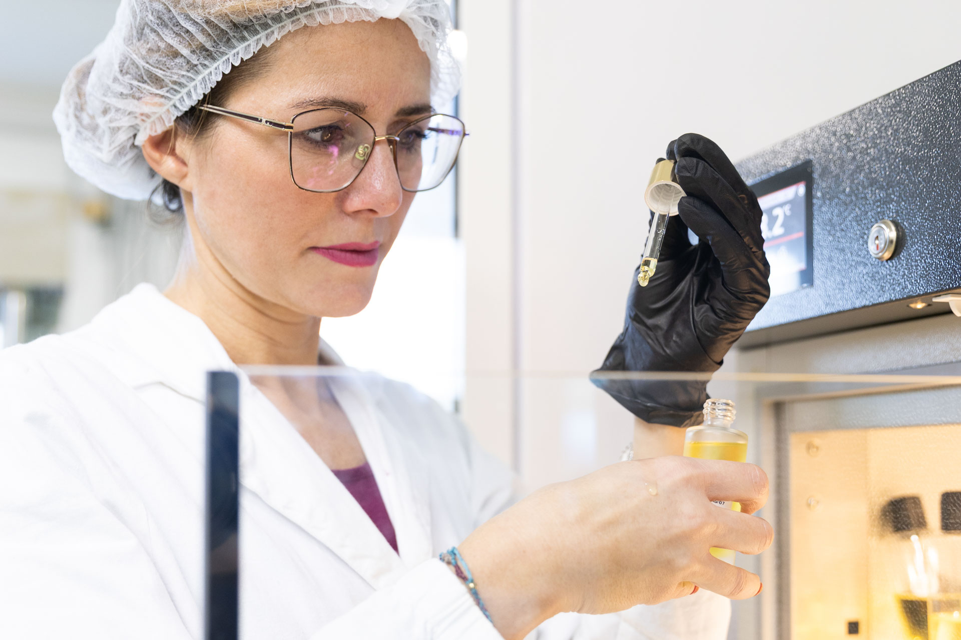 Ricercatrice in laboratorio che formula un'olio essenziale, dosando gli ingredienti con precisione scientifica.